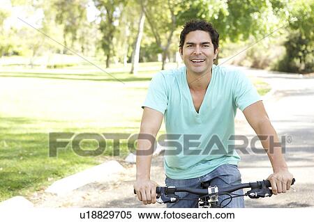 Stock Photography - Young Man Riding Bike In Park. Fotosearch