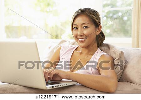Stock Image - Young Woman Using Laptop At Home. Fotosearch