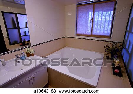 Stock Photo - Bathroom containing a bathtub with candles and flowers next to it, and a sink. Fotosearch
