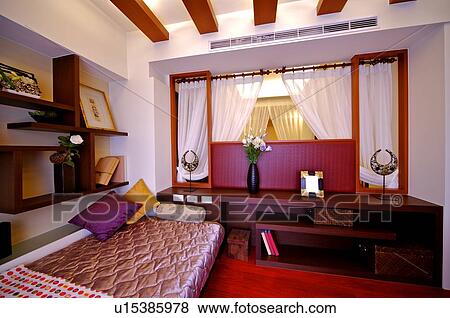 Stock Photo - Bright room with a bed against a shelf, and ornaments on shelves. Fotosearch
