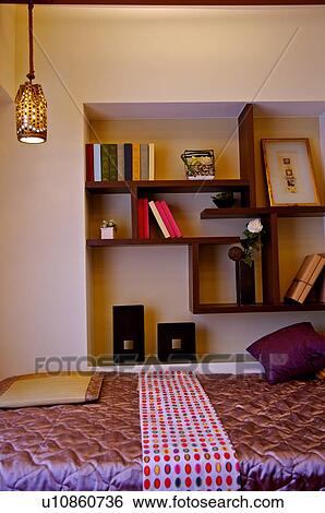 Colorful bed beside shelves with ornaments and books on display View Large Photo Image Stock Photograph - Colorful bed beside shelves with ornaments and books on display. Fotosearch