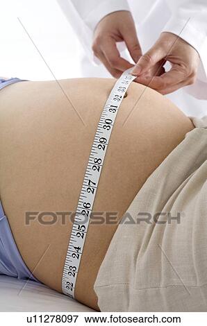 Close-up of a doctor measuring the abdomen of a pregnant young woman View Large Photo Image Stock Photo - Close-up of a doctor measuring the abdomen of a pregnant young woman. Fotosearch