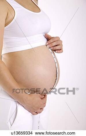 Pregnant woman measuring abdomen with tape measure, close-up View Large Photo Image Picture - Pregnant woman measuring abdomen with tape measure, close-up. Fotosearch