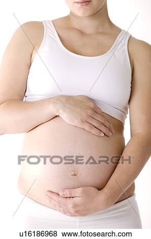 Stock Photo - Pregnant young woman with her hands on her abdomen, close-up. Fotosearch