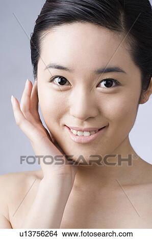 Picture - A oriental woman putting her hand on her right cheek. Fotosearch