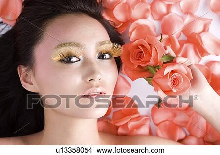 Picture - Young woman amongst rose petals. Fotosearch