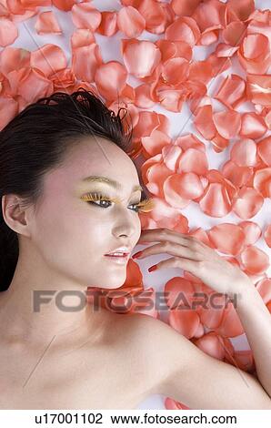 Stock Image - Young woman amongst rose petals. Fotosearch
