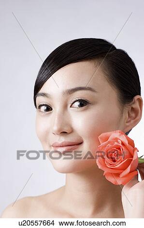 young woman holding a rose on her left side View Large Photo Image Picture - young woman holding a rose on her left side. Fotosearch