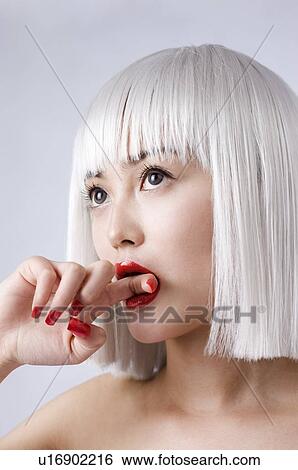 Stock Photograph - Young woman wearing white wig biting her forefinger. Fotosearch