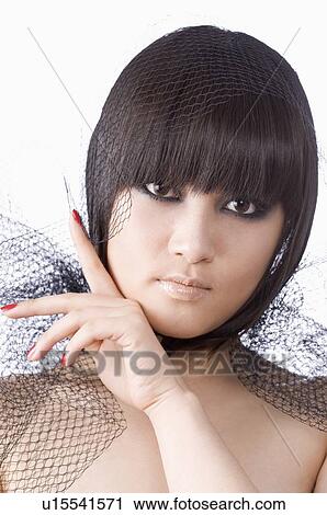 Stock Image - Young woman with black yarn on her head and shoulders. Fotosearch