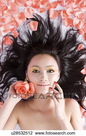 Stock Image - Young women amongst rose petals. Fotosearch