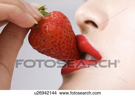 Picture - Young women eating strawberry. Fotosearch