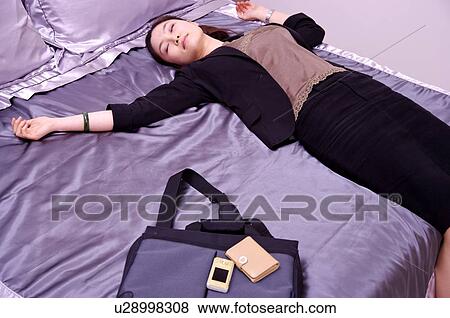 Stock Photo - Young woman lying on bed sleeping. Fotosearch
