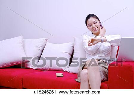 Stock Image - Young woman on the phone looking at watch. Fotosearch