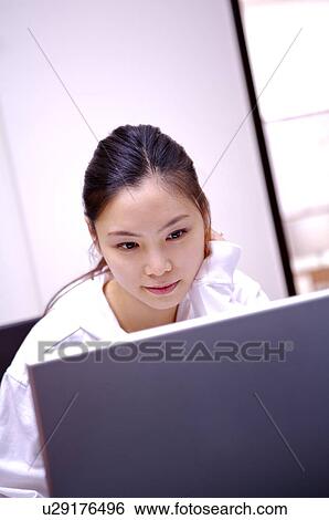Stock Photograph - Young woman working on laptop at home. Fotosearch