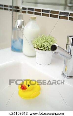 Stock Image - Rubber duck floating in the washbowl. Fotosearch