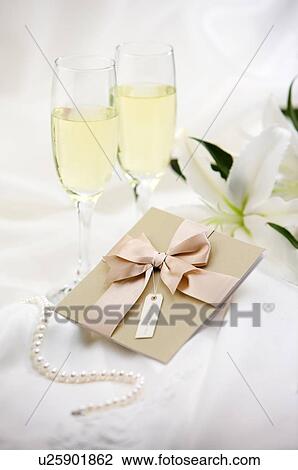 Stock Image - Champagne and wedding invitation on fabric. Fotosearch
