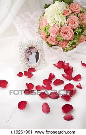 Stock Image - Wedding bouquet, rose petals and wedding pictures on fabric. Fotosearch
