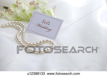 Stock Image - Wedding name tag and pearl necklace on fabric. Fotosearch