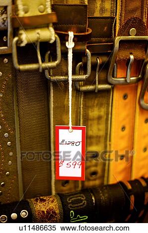 Stock Photography - Discount price tag hanging from a belt, amidst other belts. Fotosearch
