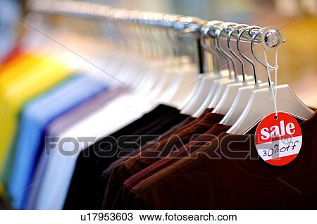 Stock Image - Discount sign at the front of a row of T-shirts. Fotosearch