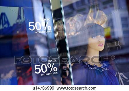 Stock Photo - Discount signs on the window of a store, with a female mannequin and handbags in the background. Fotosearch