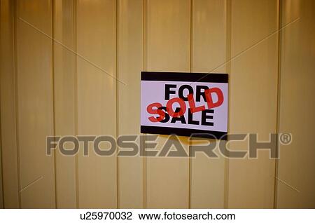 Stock Image - For Sale' sign with 'Sold' stamped across it, on a wooden wall. Fotosearch