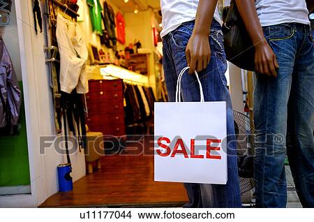 Mannequin carrying a shopping bag with a red 'Sale' sign on it, in a clothing store View Large Photo Image Picture - Mannequin carrying a shopping bag with a red 'Sale' sign on it, in a clothing store. Fotosearch