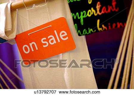 Orange and white 'On Sale' sign in front of clothes in a store View Large Photo Image Stock Photo - Orange and white 'On Sale' sign in front of clothes in a store. Fotosearch
