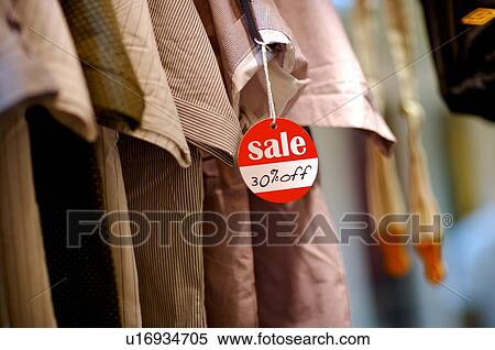 Red and white 'Sale' sign hanging from the sleeve of a shirt, among a row of shirts View Large Photo Image Stock Photography - Red and white 'Sale' sign hanging from the sleeve of a shirt, among a row of shirts. Fotosearch