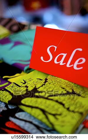 Red and white 'Sale' sign on top of colorful clothing View Large Photo Image Picture - Red and white 'Sale' sign on top of colorful clothing. Fotosearch