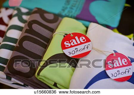 Stock Photograph - Red and white 'Sale' signs on colorful T-shirts. Fotosearch