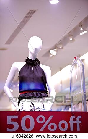 Stock Photograph - Red discount sign on a window, in front of a female mannequin wearing a purple top. Fotosearch