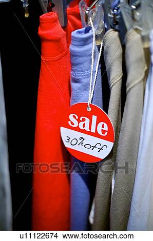 Red 'Sale' sign hanging in front of a row of pants View Large Photo Image Picture - Red 'Sale' sign hanging in front of a row of pants. Fotosearch