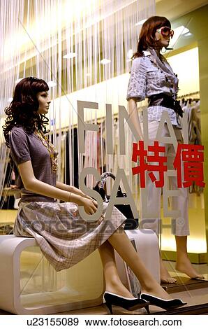 Stock Photo - Window of a clothing store with mannequins, with English and Chinese text indicating a sale. Fotosearch