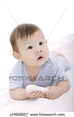 Stock Photo - Baby boy lying on his front, holding a boy. Fotosearch