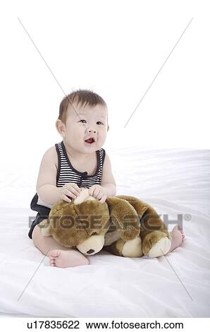 Baby boy sitting upright, playing with a brown teddy bear View Large Photo Image Stock Image - Baby boy sitting upright, playing with a brown teddy bear. Fotosearch