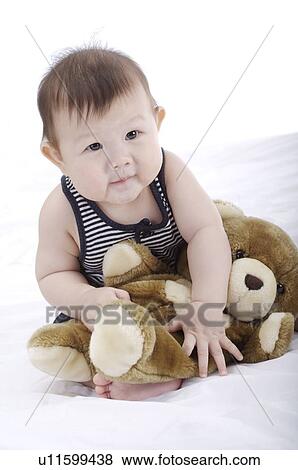 Baby boy sitting upright, playing with a brown teddy bear View Large Photo Image Stock Photo - Baby boy sitting upright, playing with a brown teddy bear. Fotosearch