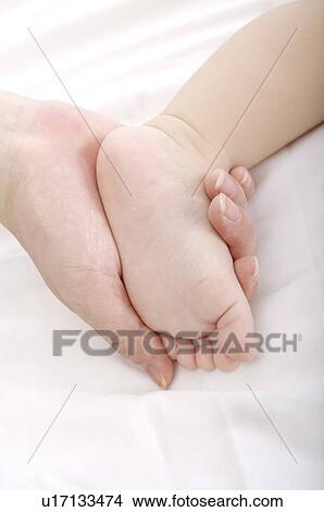 Mother holding a baby's foot in her hand View Large Photo Image Picture - Mother holding a baby's foot in her hand. Fotosearch