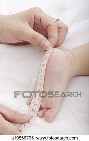 Mother measuring a baby boy's foot with tape measure, close-up View Large Photo Image Stock Photography - Mother measuring a baby boy's foot with tape measure, close-up. Fotosearch