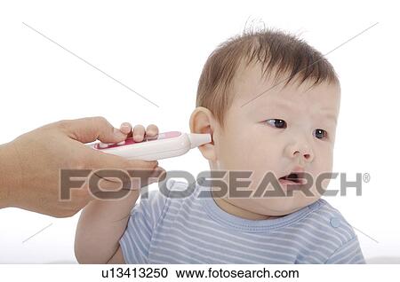 Stock Image - Mother measuring the ear temperature of a baby boy with a thermometer. Fotosearch
