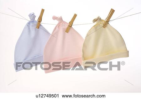 Stock Image - Three pieces of baby clothing hanging from a clothesline, in a row. Fotosearch