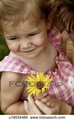 Picture - Mother holding a toddler with a flower in her hand. Fotosearch