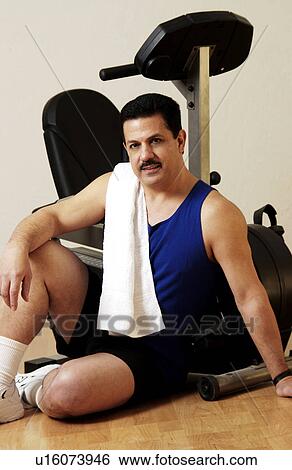 Stock Photograph - Man relaxing next to exercise bike. Fotosearch