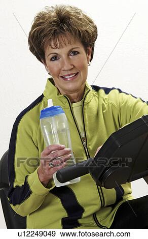 Stock Photo - Senior woman exercising on exercise bike. Fotosearch