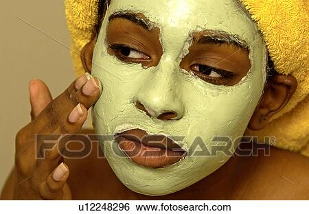 Stock Photograph - Woman putting on a facial mask. Fotosearch
