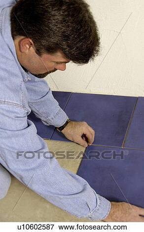 Stock Photo - Man laying ceramic tile. Fotosearch