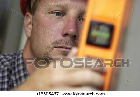 Man with hard hat using level View Large Photo Image Stock Photo - Man with hard hat using level. Fotosearch