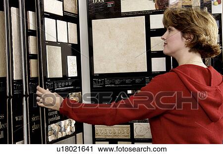 Stock Image - Woman looking at flooring samples. Fotosearch