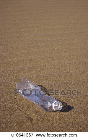 Stock Photo - Crumpled plastic bottle, lying on smooth sand. Fotosearch